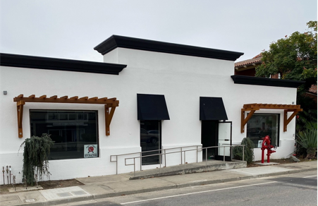 a white building with black awnings and a red fire hydrant